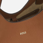 The gold-tone metallic logo on the front of the BOSS Lenah Brown Leather New Tote Bag with Metallic Logo.