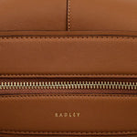 Radley brand name embossed in gold foil on the front of the Westwell Lane Toffee Brown Leather Large Zip Top Shoulder Bag.