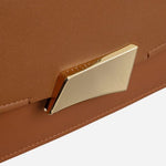 Branded plate hardware on the front of The Belsize Toffee Brown Leather Small Flapover Shoulder Bag.