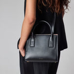 The adjustable and detachable strap, and the grab handles on the Paul Smith Women's Black Leather Top Handle Bag with 'Signature Stripe' Trims.