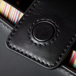 The magnetic tab closure on the Paul Smith Women's Black Leather Top Handle Bag with 'Signature Stripe' Trims.