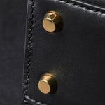 The gold-tone bag studs at the base of the Paul Smith Women's Black Leather Top Handle Bag with 'Signature Stripe' Trims.