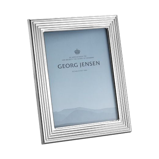 This Bernadotte Small Picture Frame 4x6" by Georg Jensen has a mirrored stainless steel frame with a ridged edge.