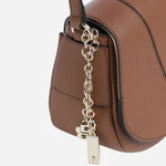 Side view of the charms on the BOSS Salley Brown Saddle Bag with Metal Logo.