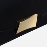 Branded plate hardware on the front of the The Belsize Black Leather Small Flapover Shoulder Bag.