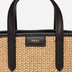 The BOSS gold-tone metal logo on the front of the BOSS Jala Woven Cross Body Bag with Metal Logo.