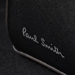 Close up of the Paul Smith logo embossed in silver foil on the side of the Paul Smith Signature Stripe Coated Canvas Flight Bag.