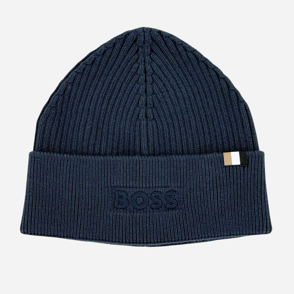 A dark navy blue ribbed knit beanie hat with a folded cuff. The cuff features an embossed BOSS logo patch on the left side and a small white and navy striped brand tag on the right side.