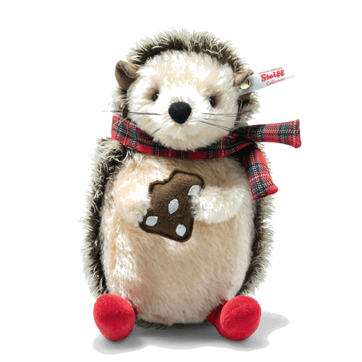 This Steiff Ivo the Christmas Hedgehog, 19 cm is seen eating a gingerbread biscuit with a scarf wrapped around his neck.